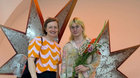Foto von Rektorin Ulrike Kuch mit Kunsthalle Wien Preisträger*in Valentino Skarwan vor einem der Werke.