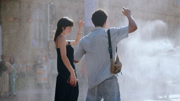 A man and
                                          a woman are standing in front of the OKP site, outside the University of Applied Arts building, pointing into the air
