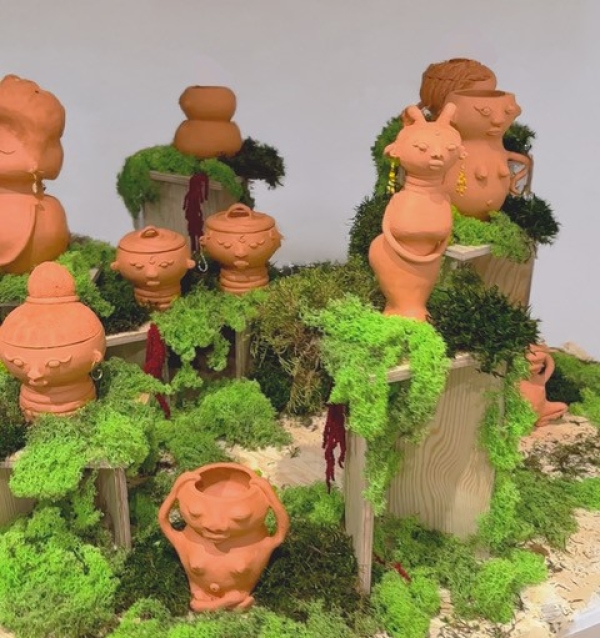Tonfiguren auf Moos und Holzobjekten ausgestellt