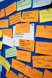 Bunte Post-its hängen an einer blauen Pinnwand