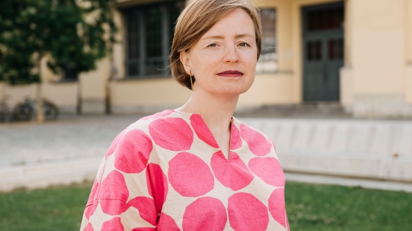 Color portrait by Ulrike Kuch in front of a green meadow with a building in the background